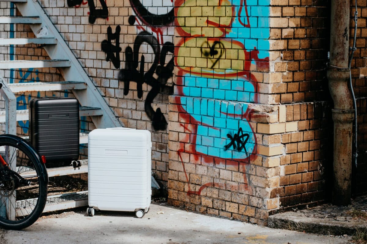 Koffer vor bunter Graffiti-Wand mit Treppe.