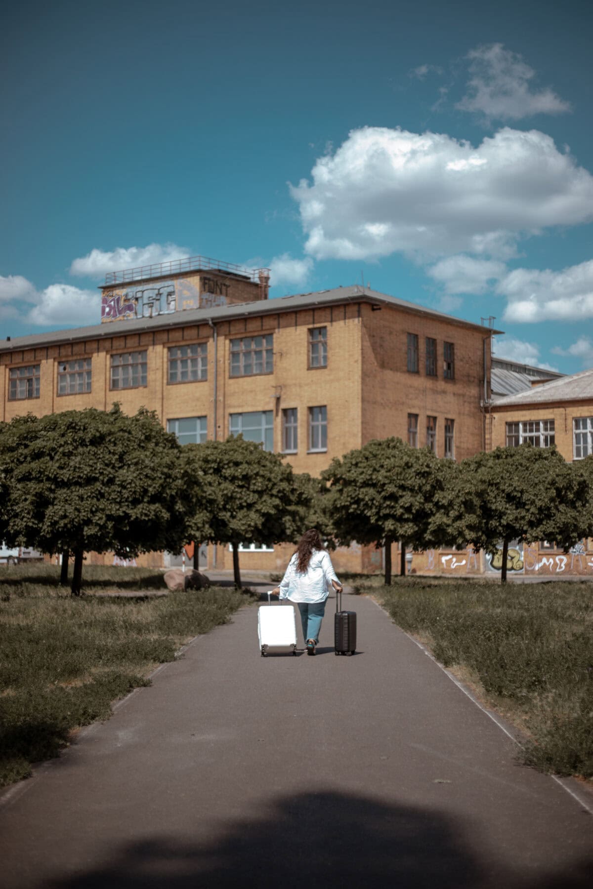 Frau zieht zwei Koffer von Horizn Studios vor historischem Gebäude.