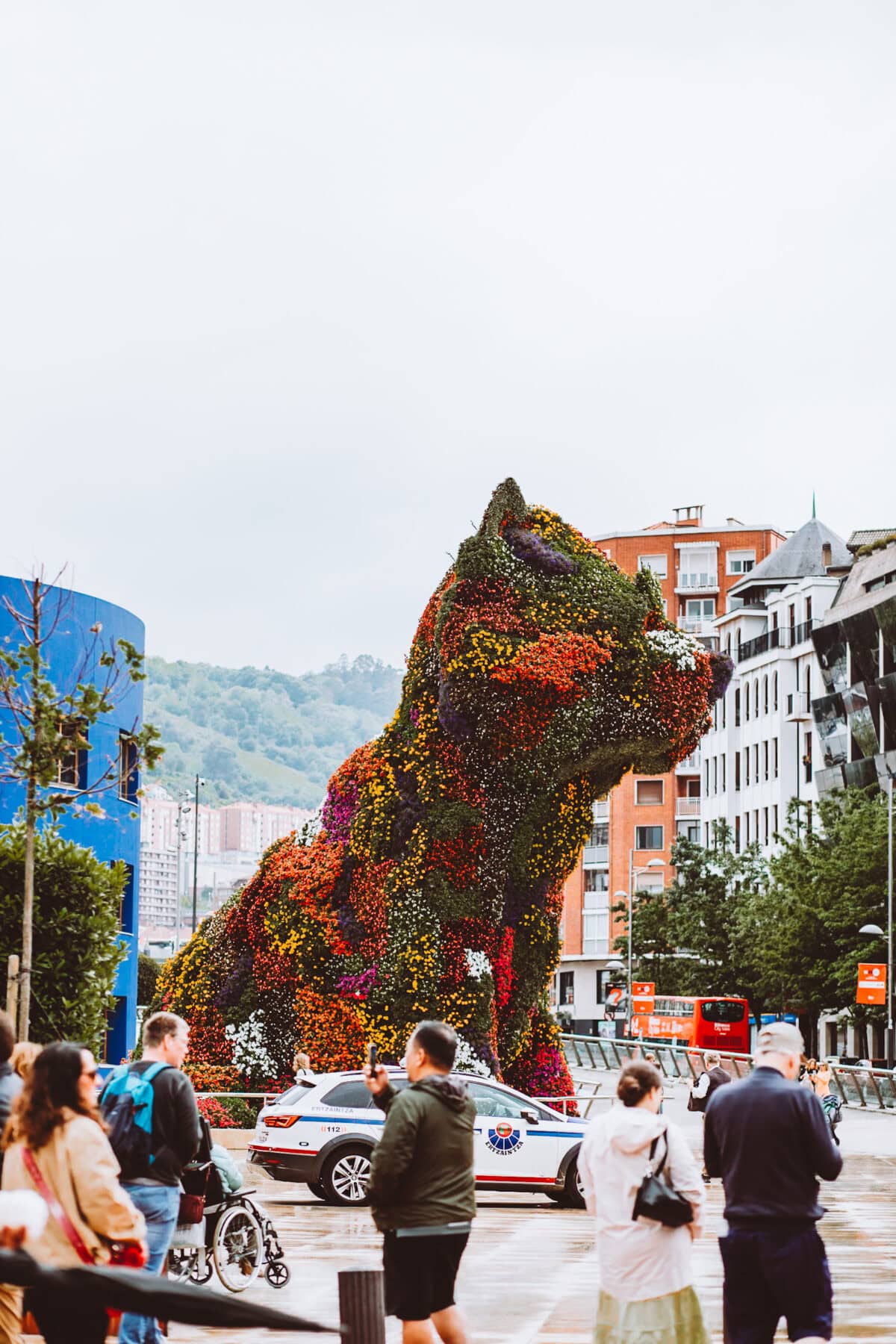 Blumenhund-Skulptur in Stadtlandschaft.