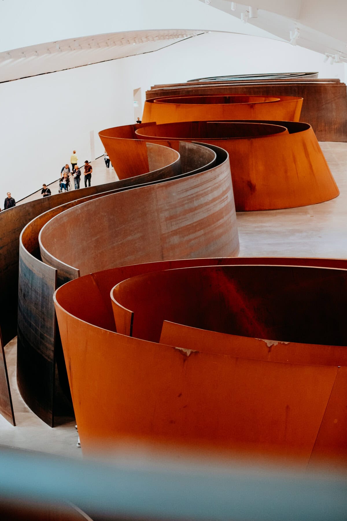 Moderne Metallskulptur in einer Galerie mit Besuchern.