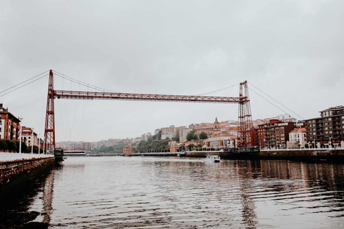 Historische Hängebrücke über Fluss in Stadtlandschaft.
