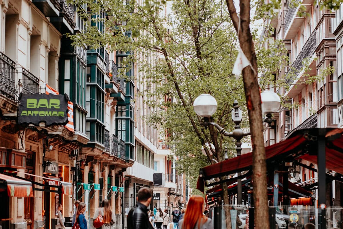 Lebhafte Straße mit Bäumen und Außenbars in der Stadt.