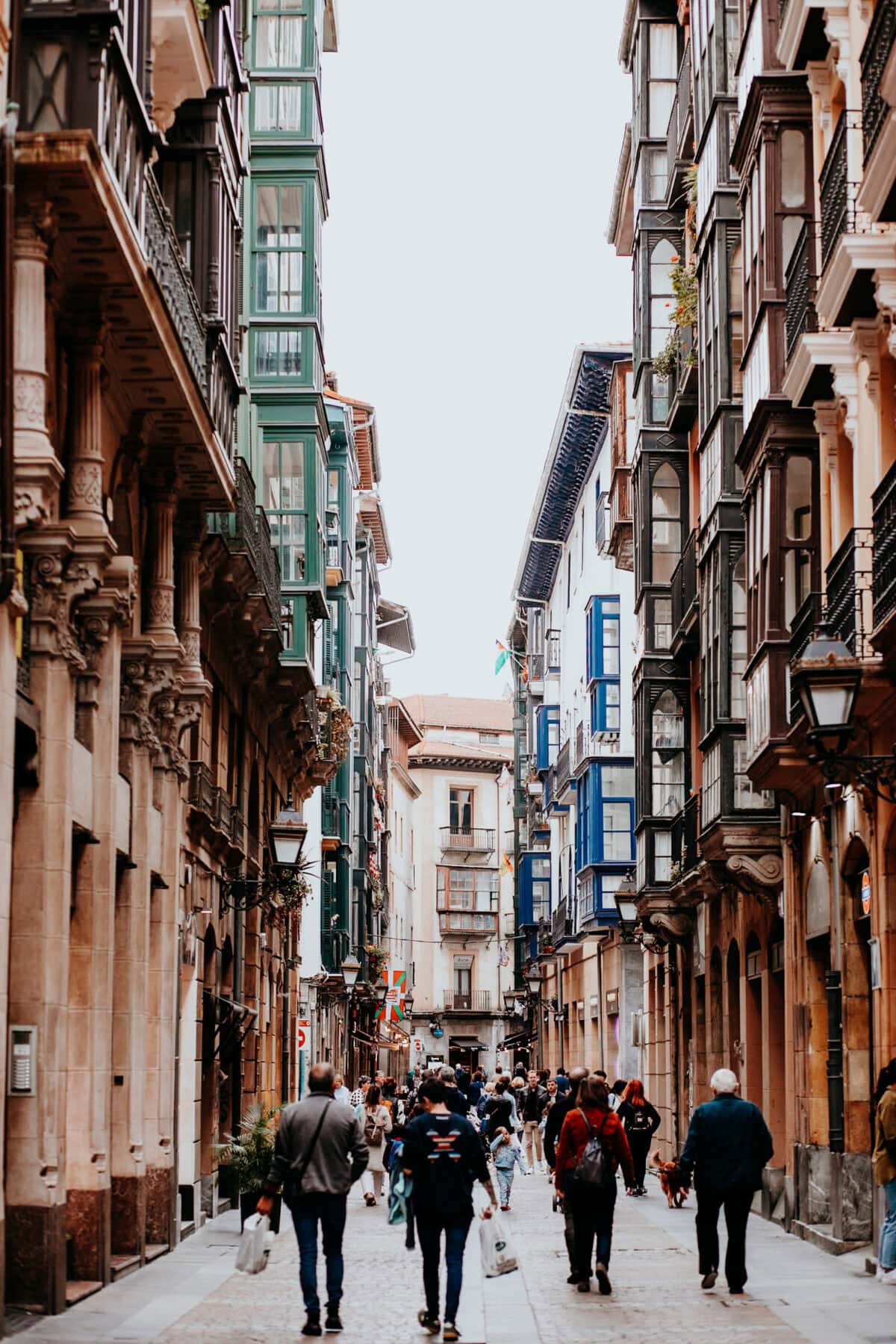 Belebte Altstadtgasse mit bunten Fassaden und Passanten.