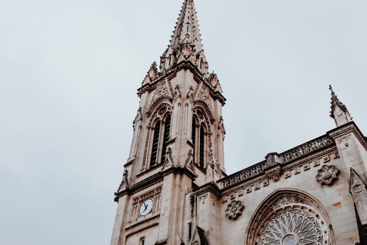 Gotischer Kirchturm mit Uhr und Rosettenfenster.