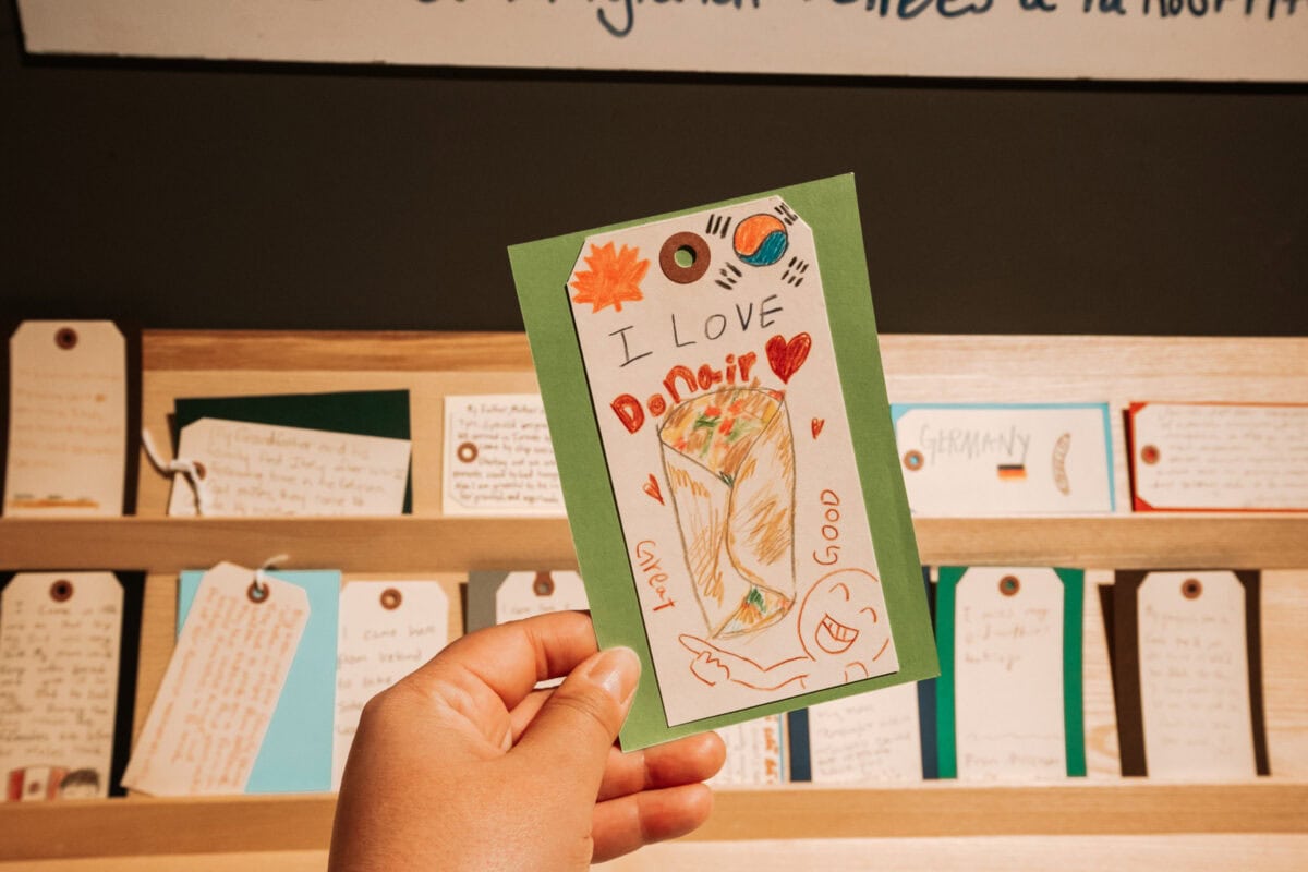 Hand hält bemalte Karte vor Regal