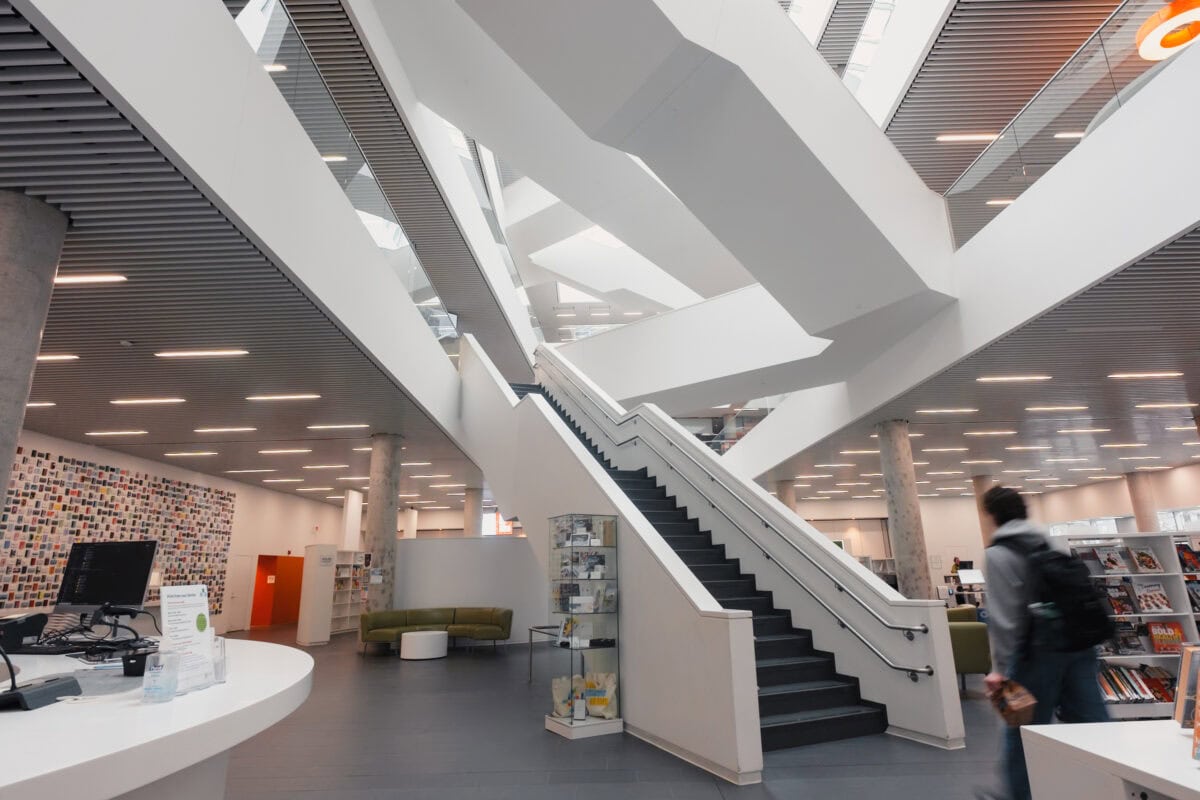 Moderne Bibliothek mit Treppe und Glaswänden.