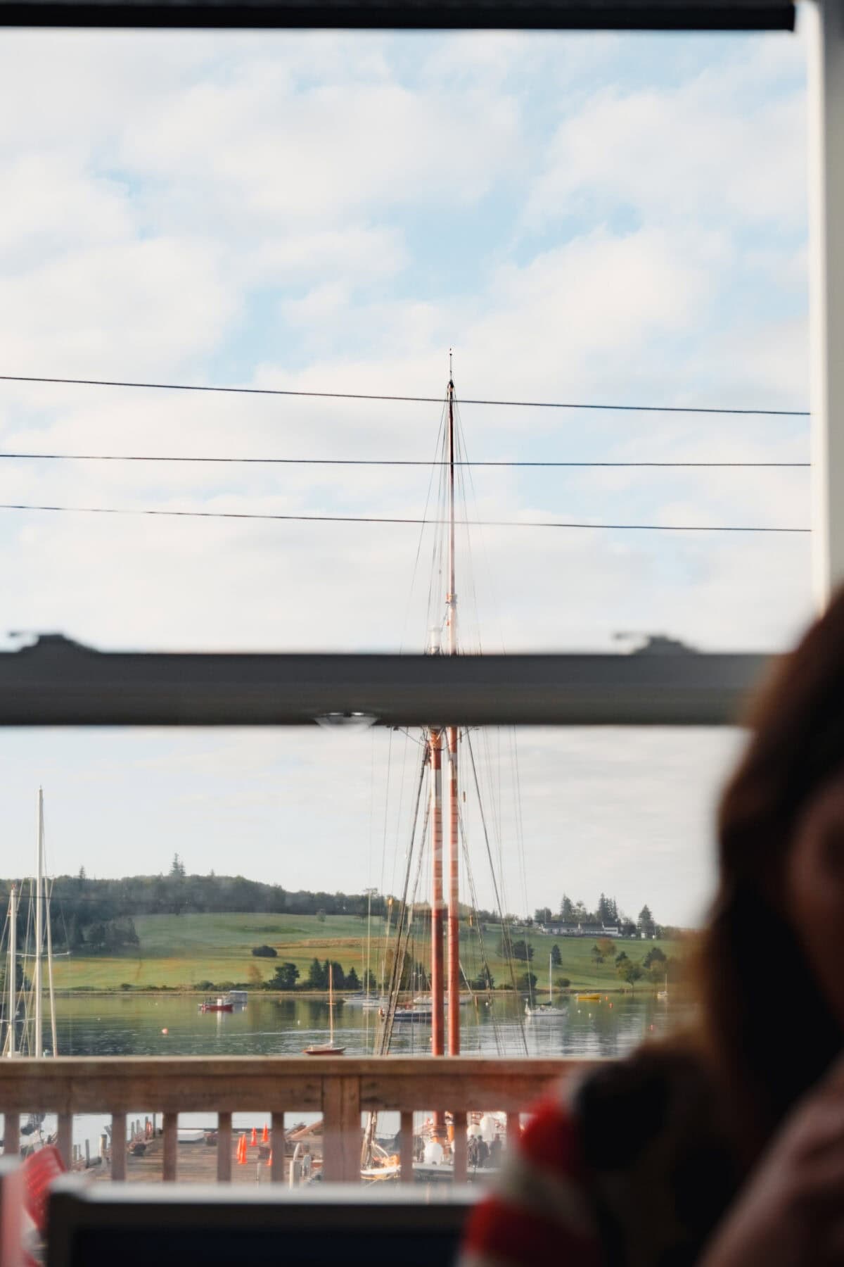 Segelmast und Landschaft am Wasser im Fensterblick