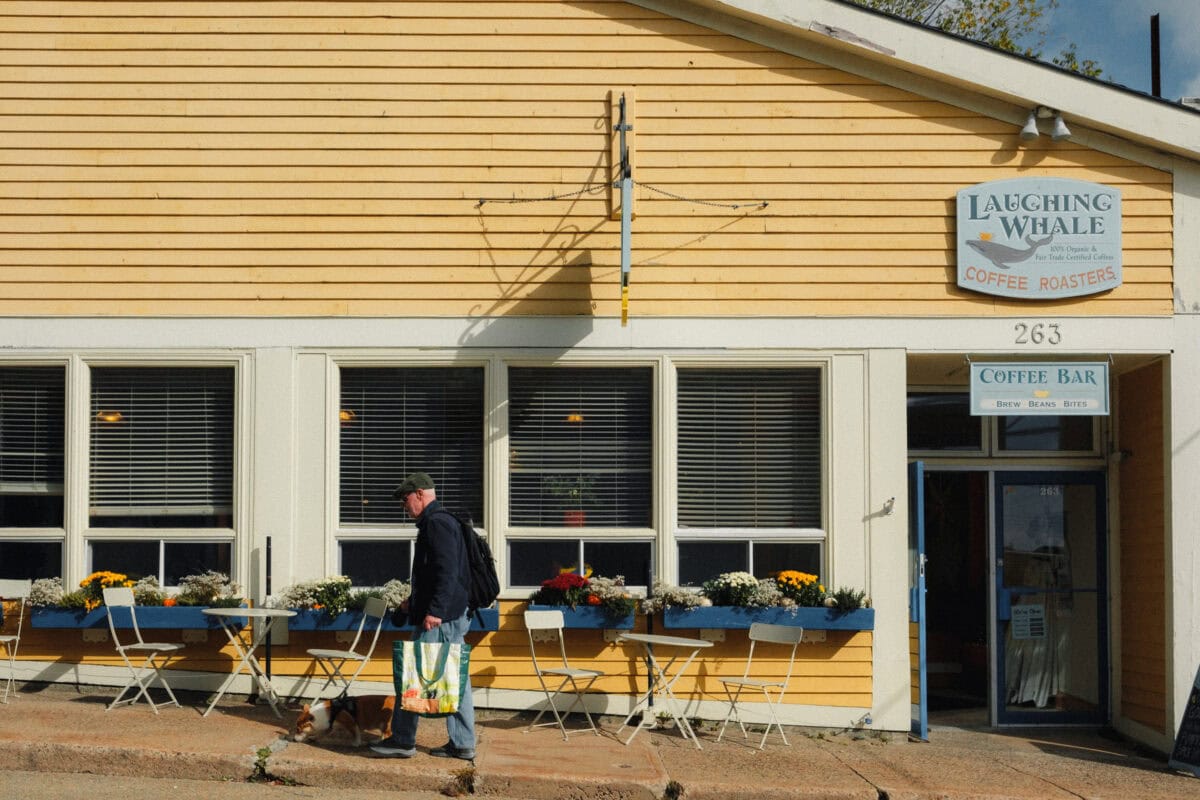 Mann mit Hund vor gelbem Café spazieren