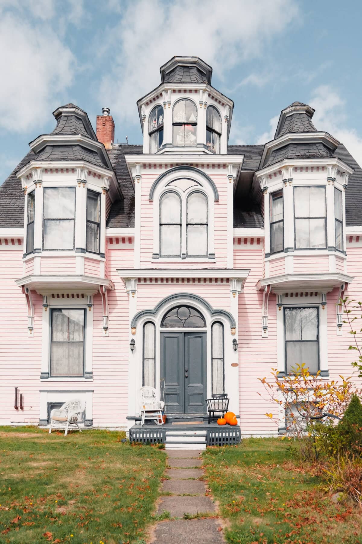 Rosa viktorianisches Haus mit Türmen und Herbstlaub.