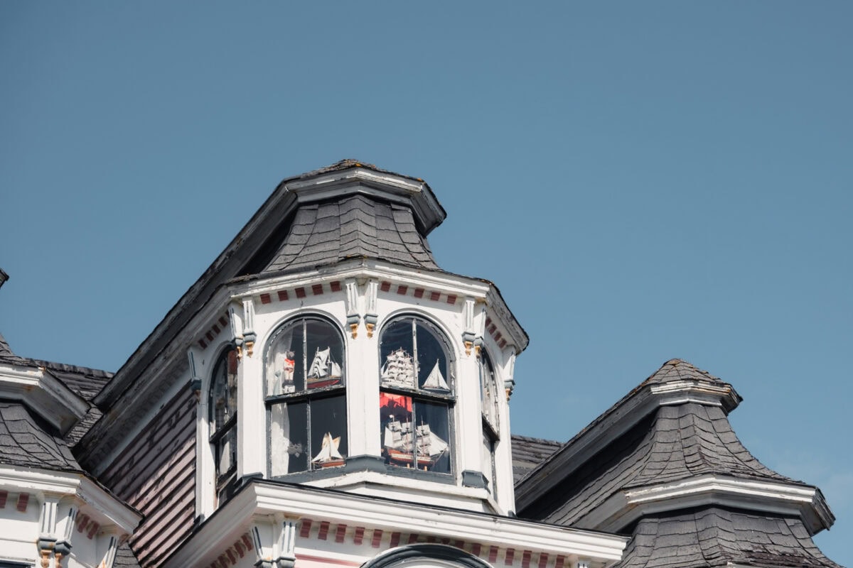 Hausdach mit Modellschiffen hinter Fenstern