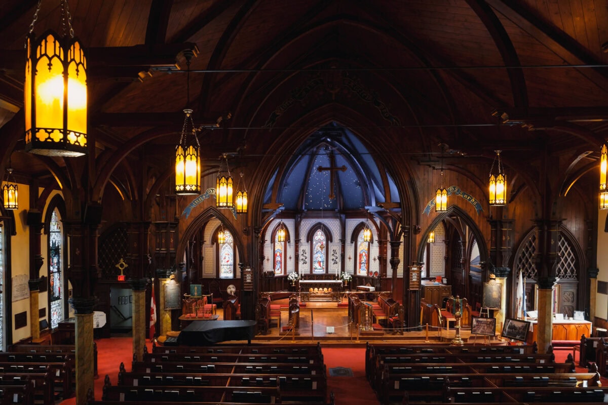 Innenraum einer alten Kirche mit Bänken und Altar.