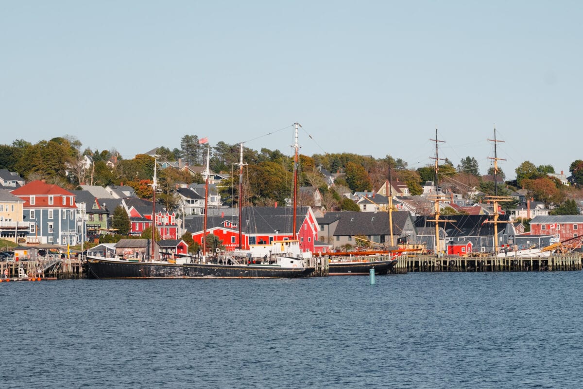 Hafenstadt mit Segelschiffen und bunten Gebäuden am Wasser.