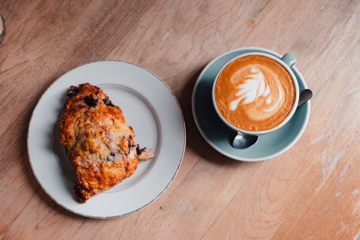 Heißer Kaffee und Gebäck auf Holztisch.