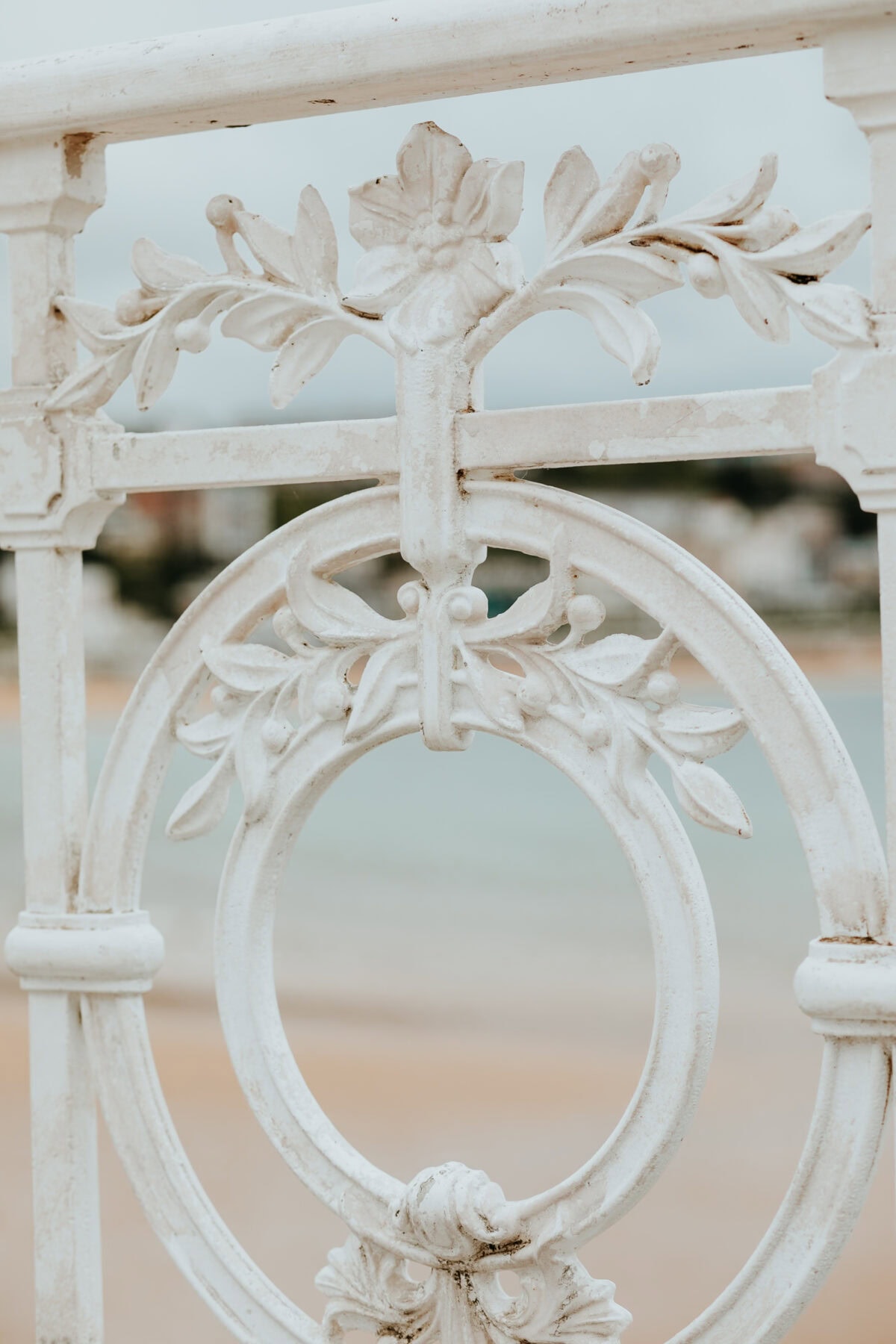 Verzierter, weißer Zaun mit Blumenmuster am Strand.