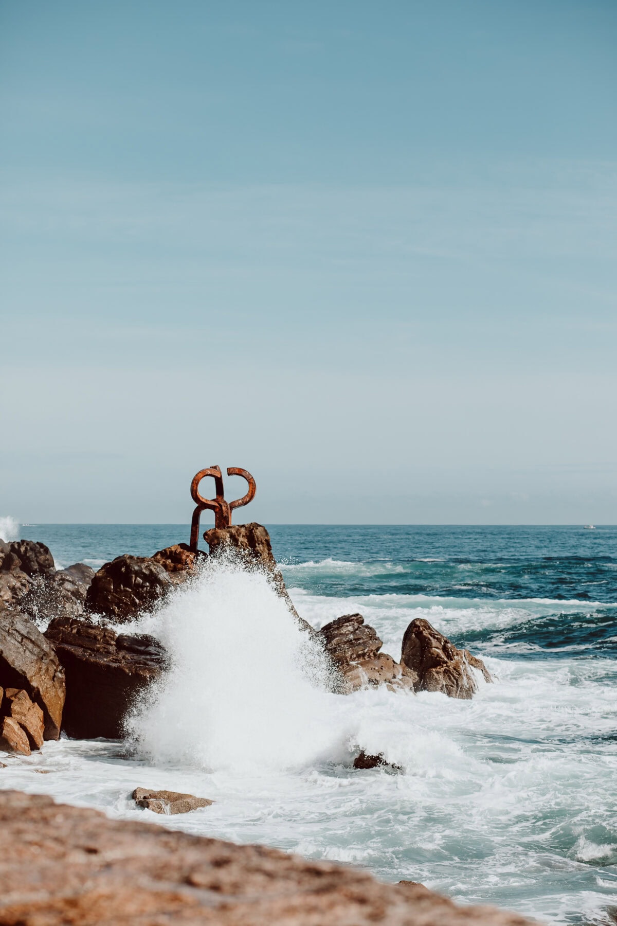 Wellen brechen an Felsen bei einer Küstenskulptur