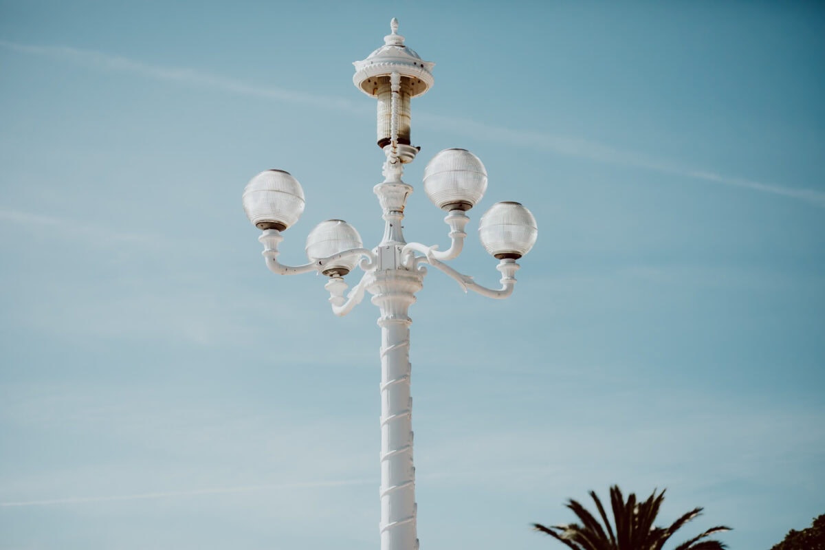 Weiße Straßenlaterne vor blauem Himmel