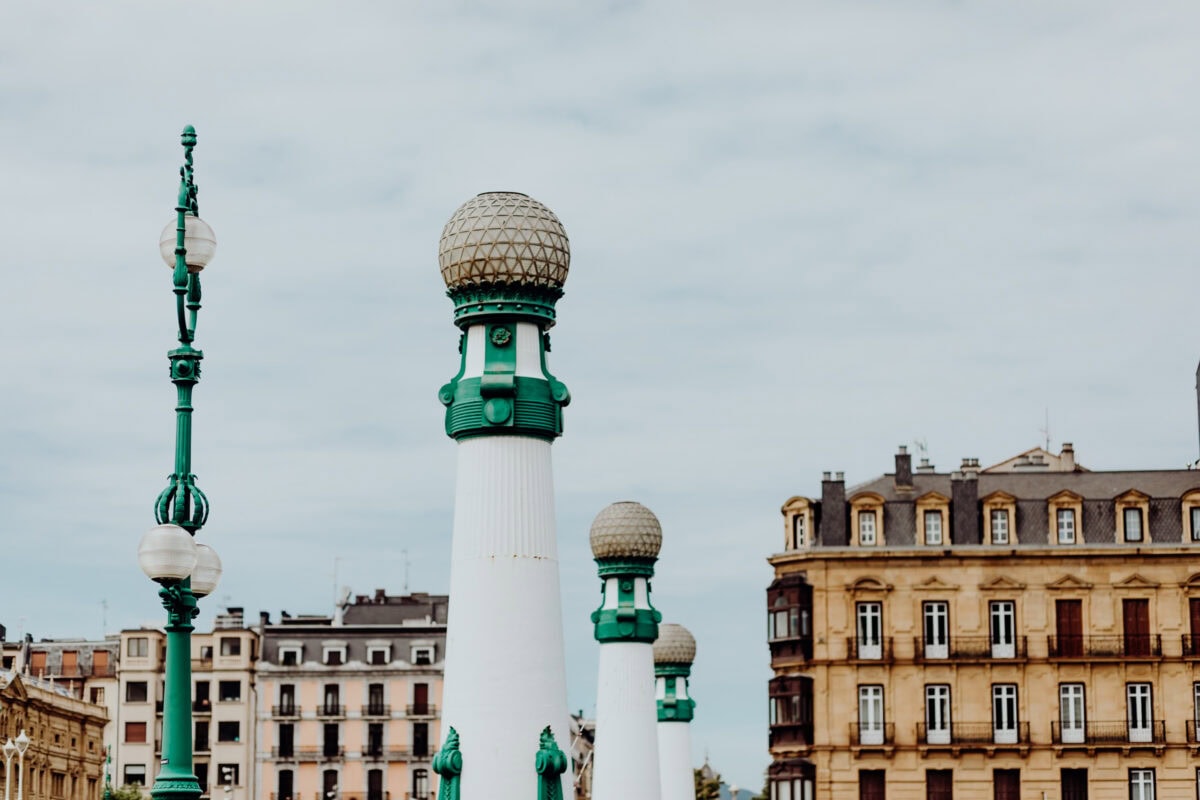 Grüne und weiße Brückenpfeiler, historische Gebäude im Hintergrund.