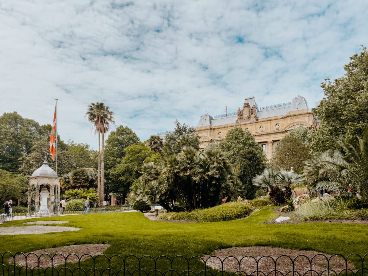 Historisches Gebäude hinter grünem Park mit Fahne.