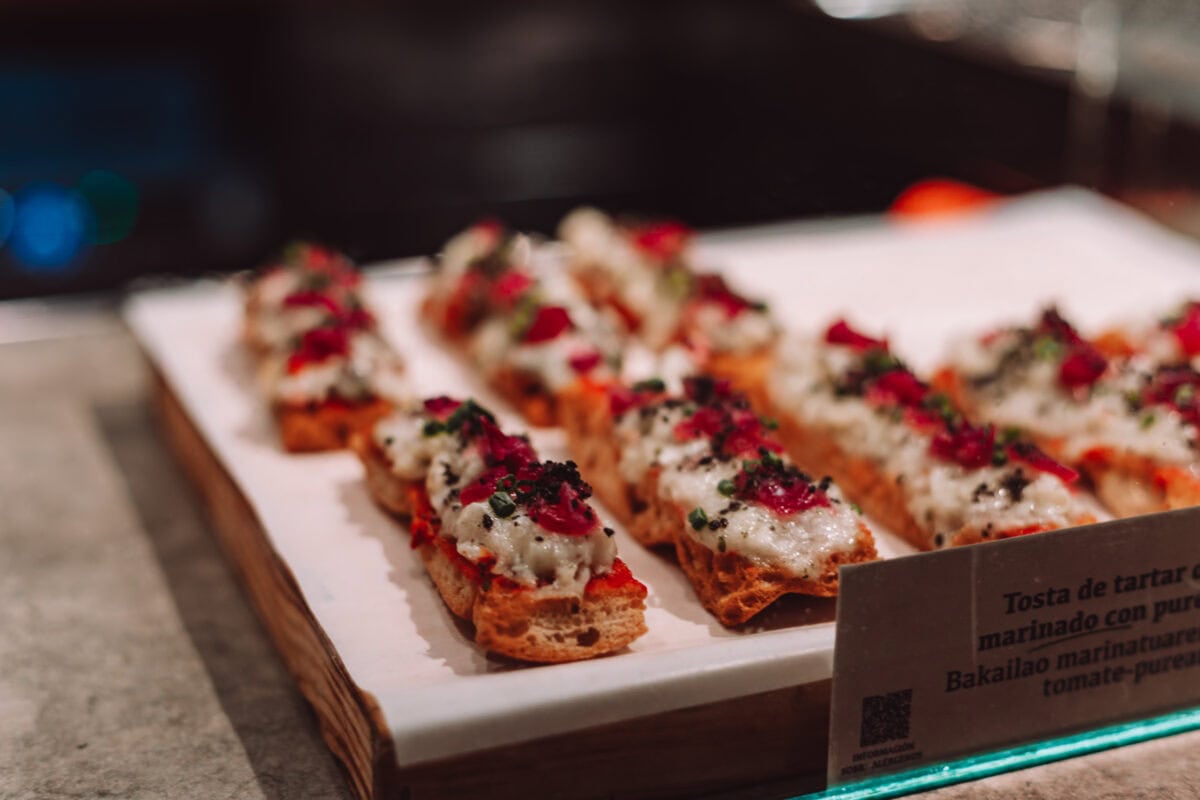 Gericht mit Brot, Tartare und Kräutern auf Tablett.