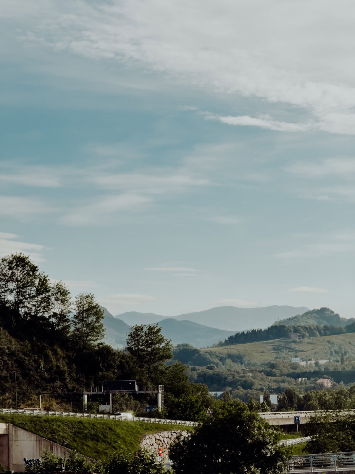 Landschaft mit Hügeln und Straße unter blauem Himmel.
