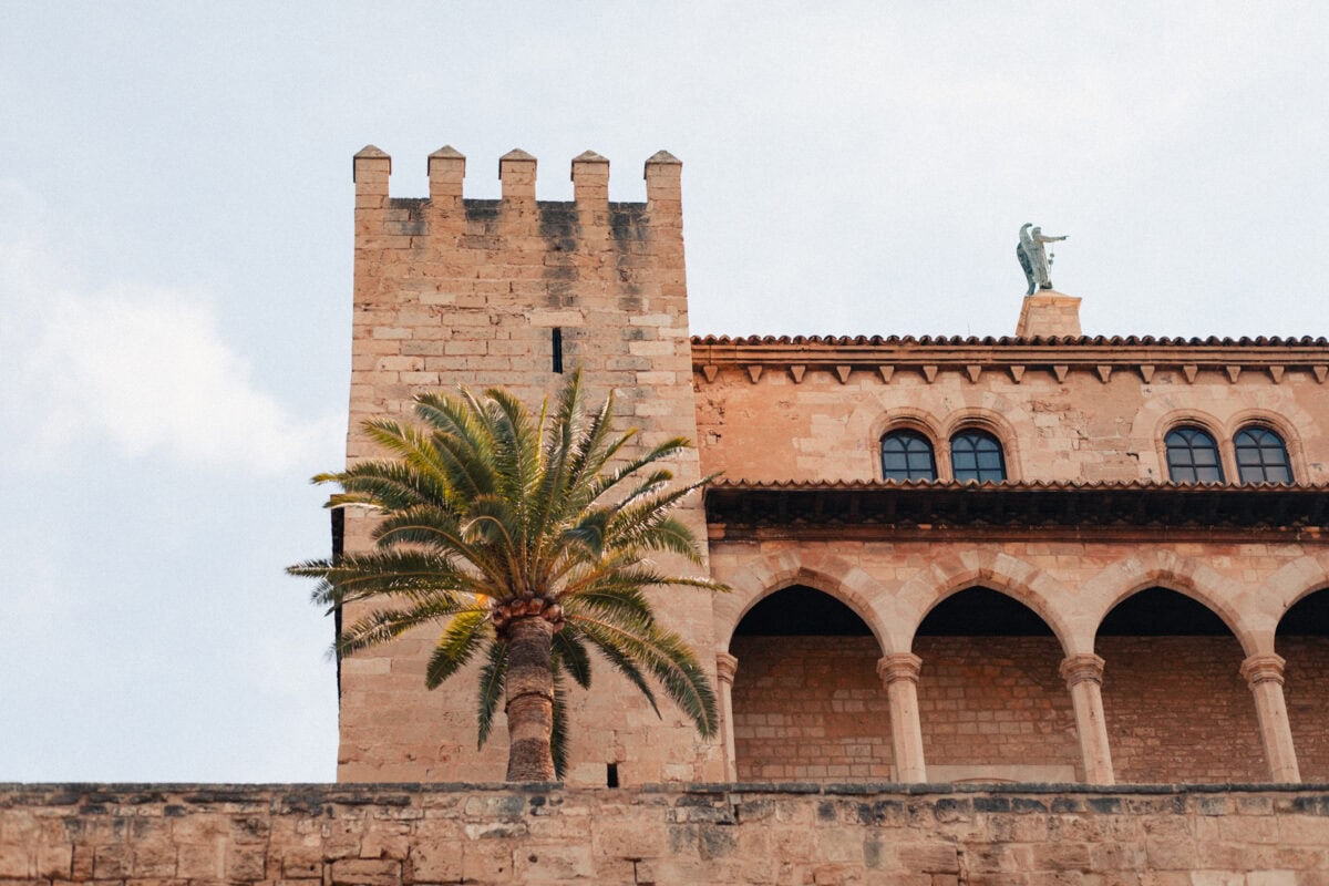 Mittelalterlicher Turm mit Palme im Vordergrund.