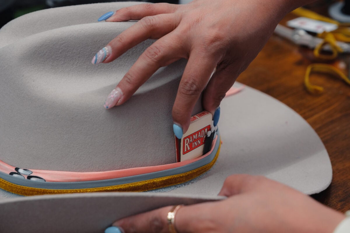 Hand mit dekoriertem Hut und Streichholzschachtel