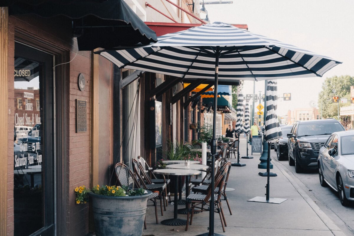 Straßencafé mit gestreiftem Sonnenschirm und Autos