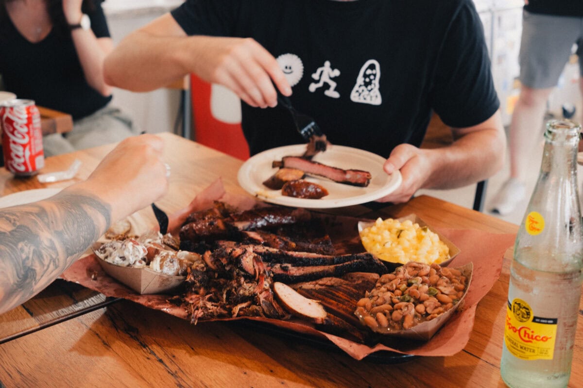 Personen essen Barbecue mit Beilagen und Getränken.