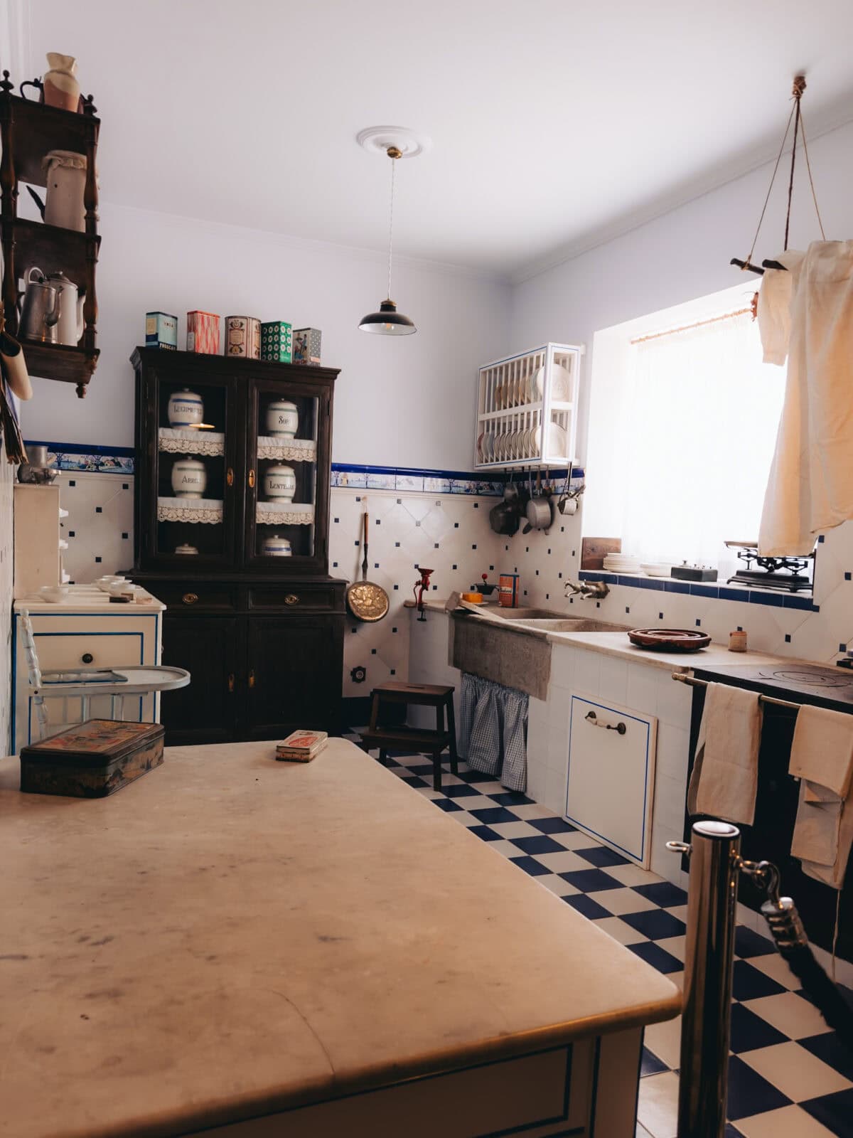 Antike Küche mit Schränken, Tisch und Utensilien.