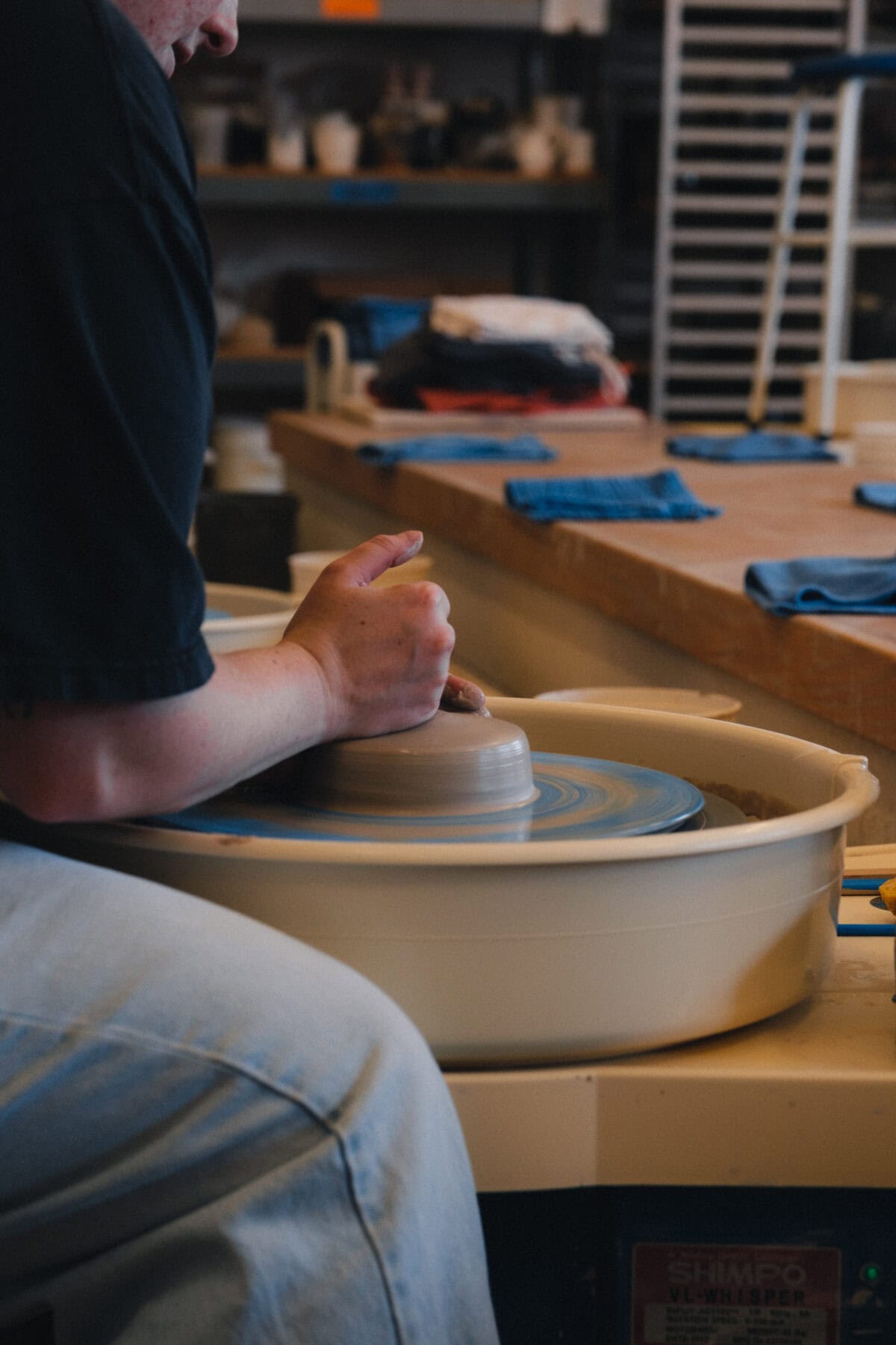 Person töpfert auf Drehscheibe in Werkstatt