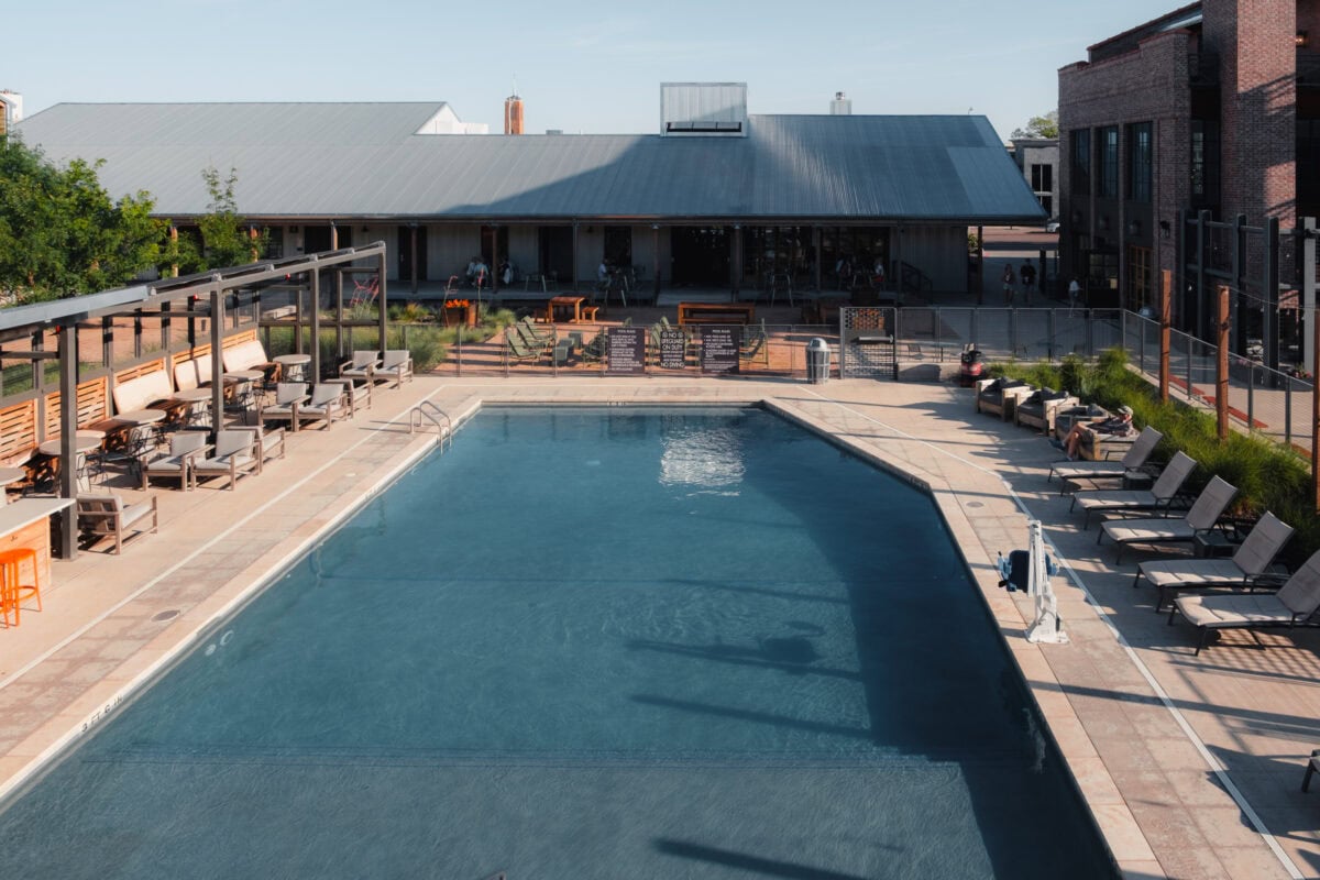 Moderner Pool mit Sitzbereich und Gebäude im Hintergrund.