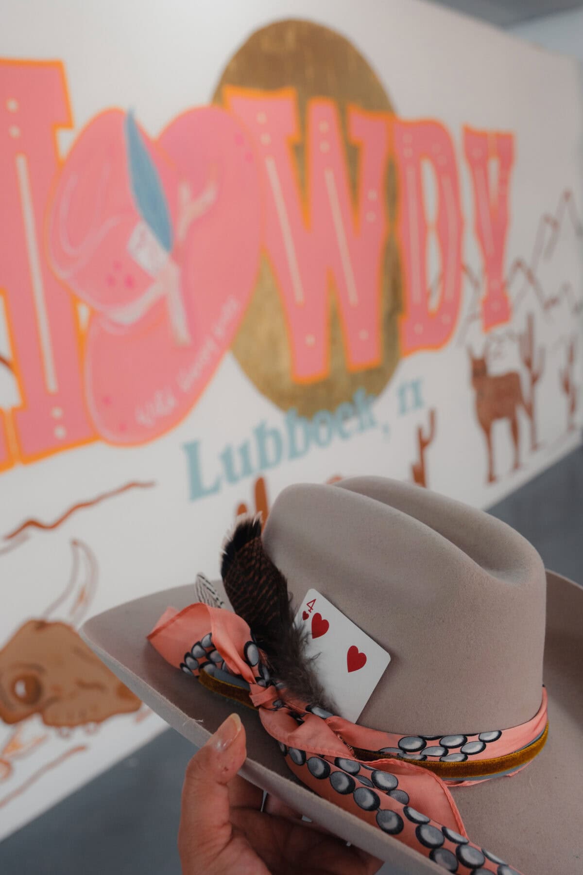 Cowboyhut mit Spielkarte vor Wandgemälde