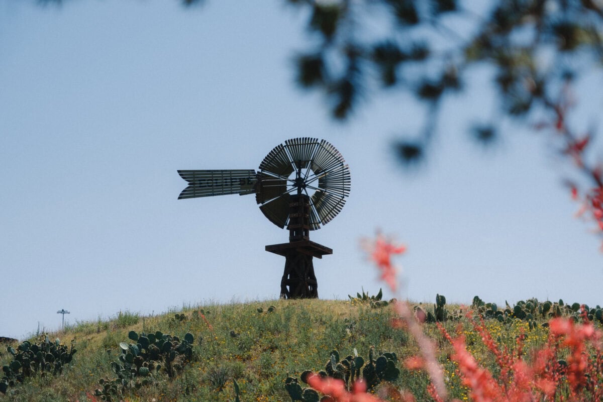 Windrad auf grünem Hügel bei blauem Himmel