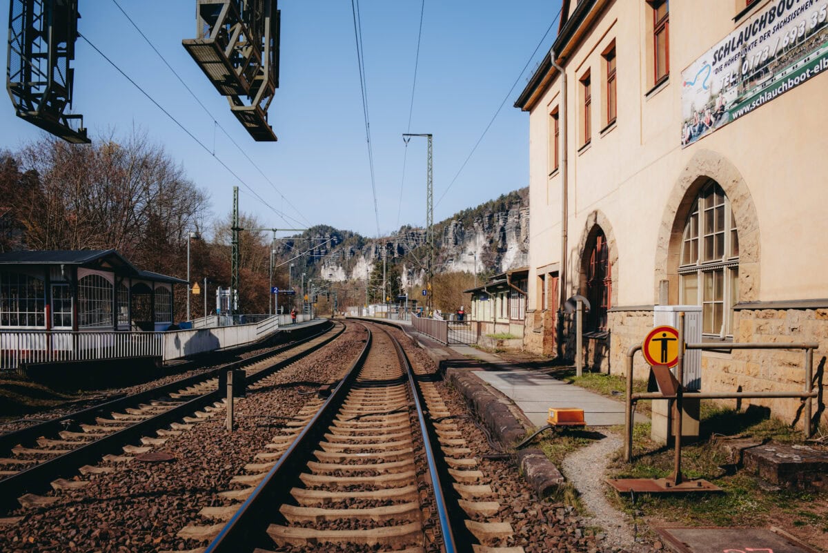 Railroad tracks at a small station in front of a rocky landscape