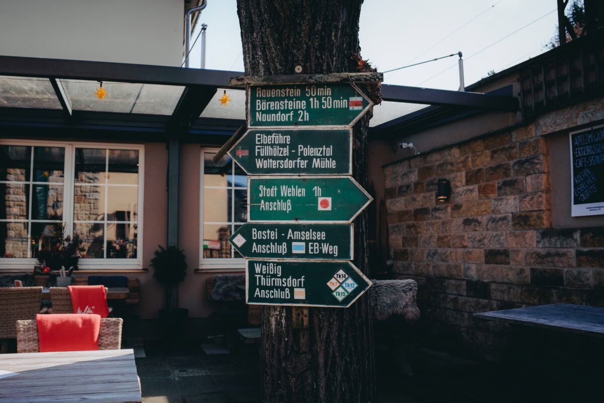 Signpost on tree in front of café terrace