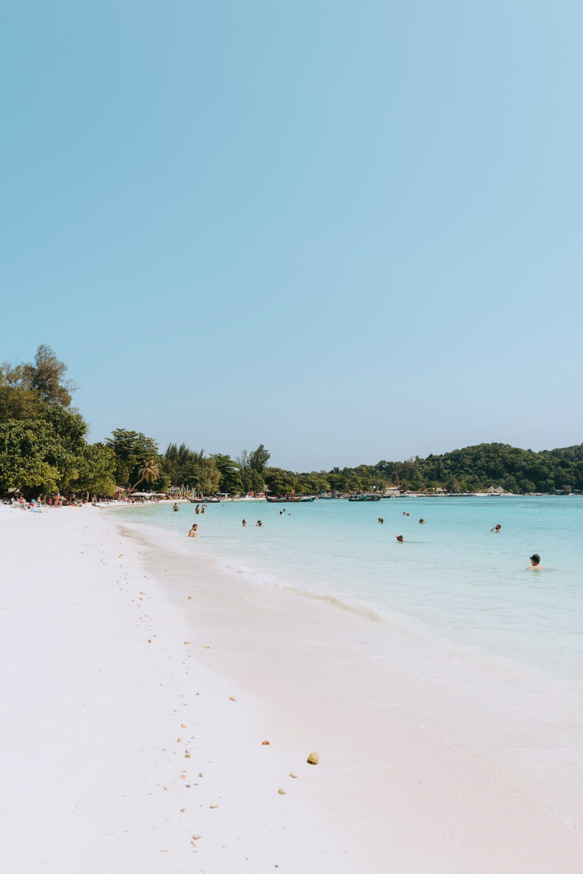 Tropischer Strand mit türkisblauem Meer und Badegästen