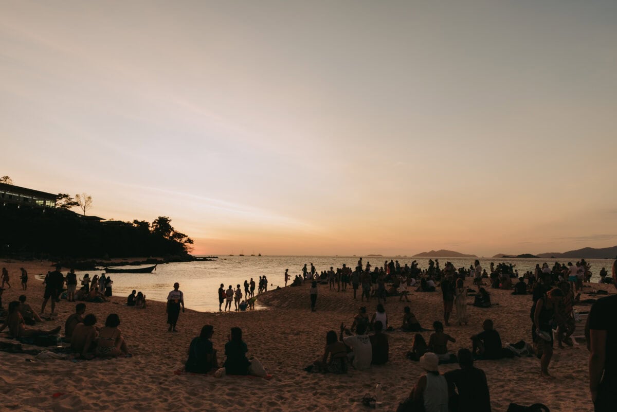 Menschen am Strand bei Sonnenuntergang am Meer