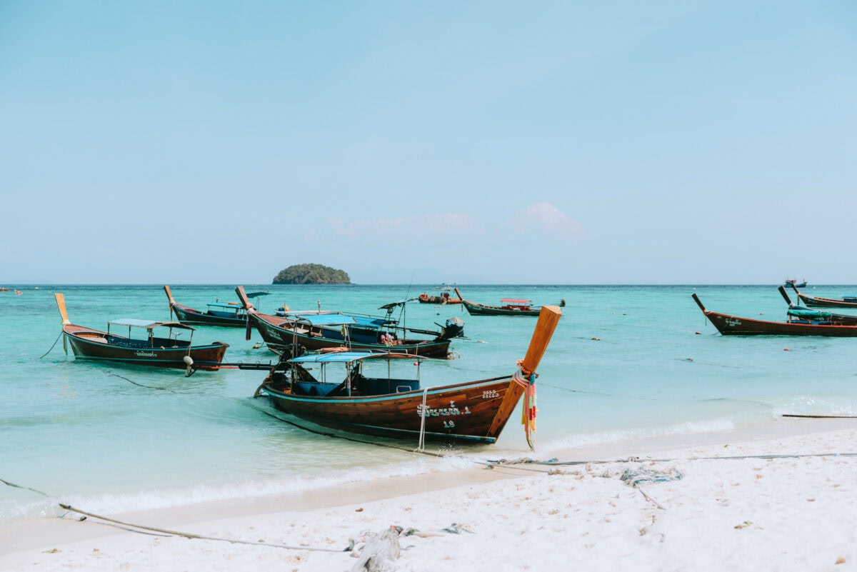 Longtail-Boote am tropischen Strand mit türkisblauem Meer