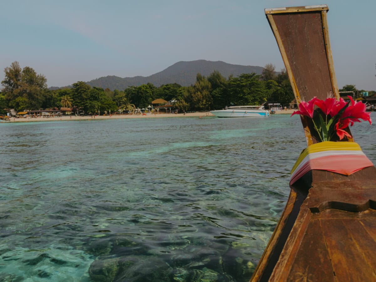 Longtail-Boot vor tropischem Strand mit türkisfarbenem Wasser