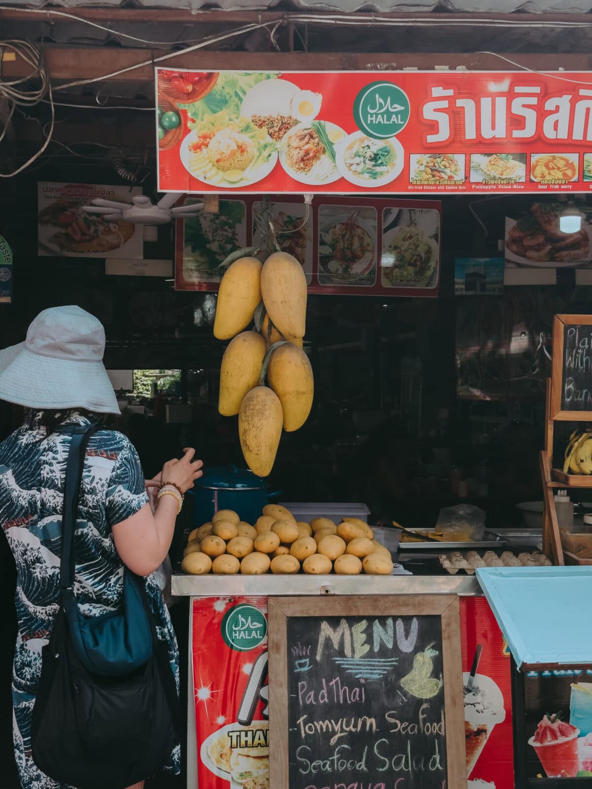 Straßenstand mit Halal-Schild und hängenden Mangos
