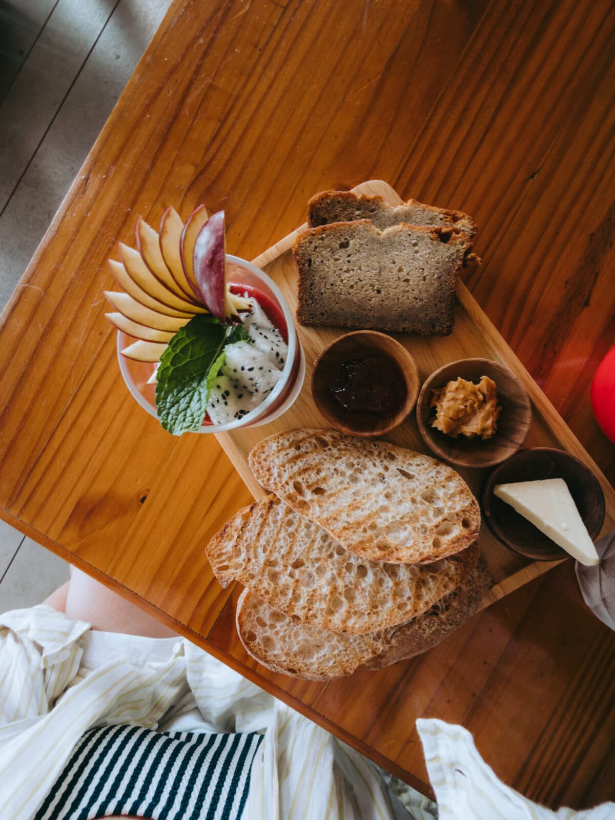 Frühstück mit Brot, Obst und Aufstrichen auf Holztisch
