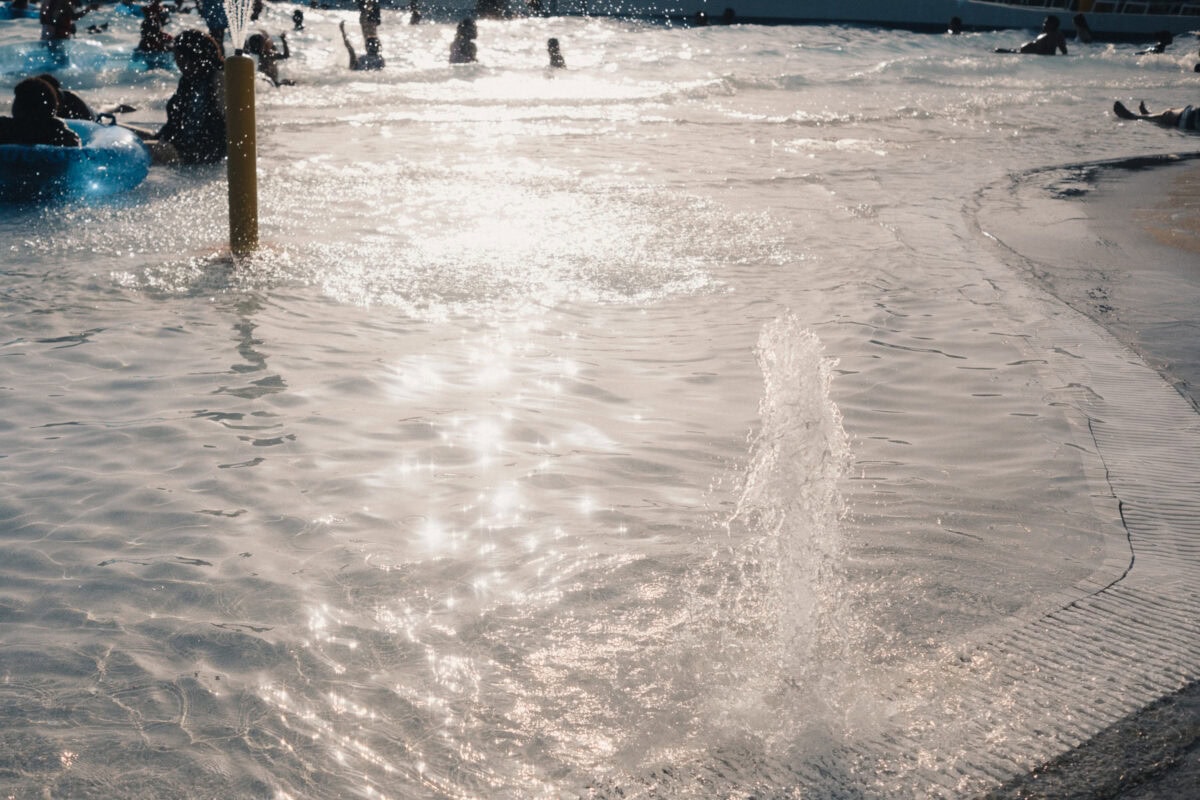Wasserfontänen im Wellenbad mit Menschen im Hintergrund