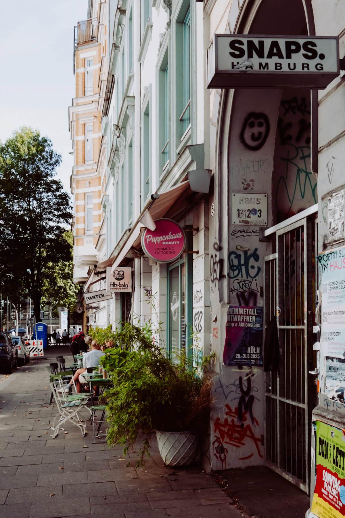 Bunte Graffiti an der Wand vor einem Café in Hamburg, lebendige Straßenszene.