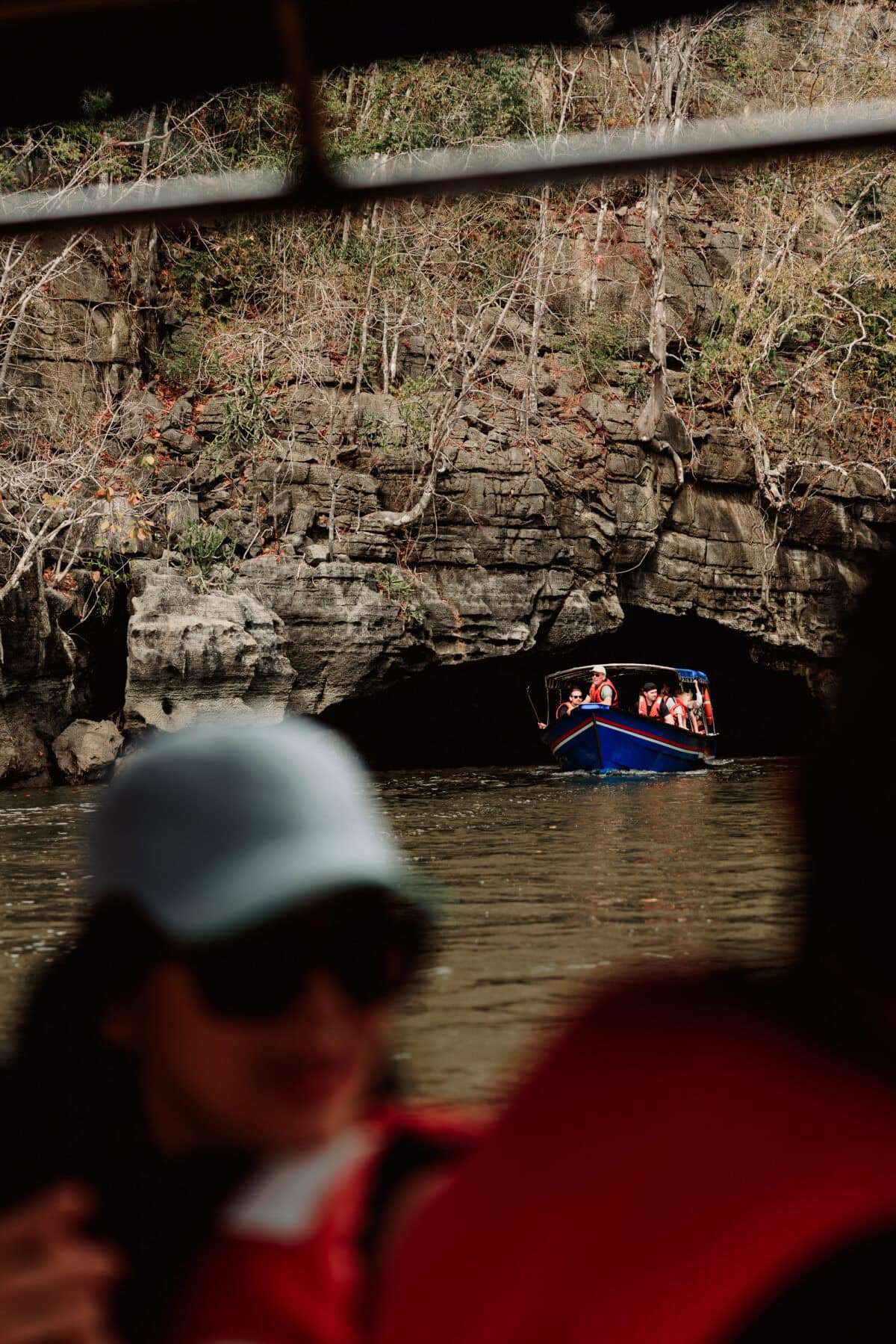 Blaues Touristenboot fährt in eine Felshöhle