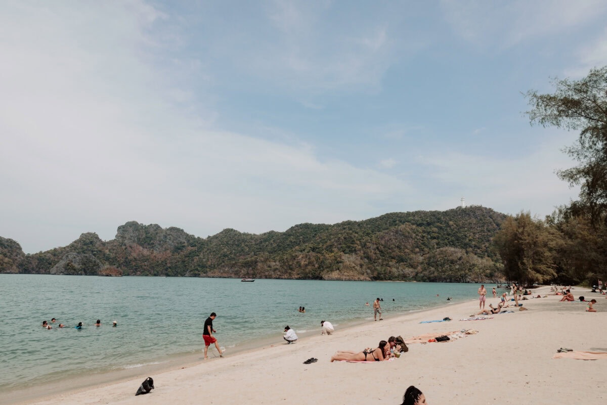 Touristen entspannen am tropischen Strand mit Bergen im Hintergrund