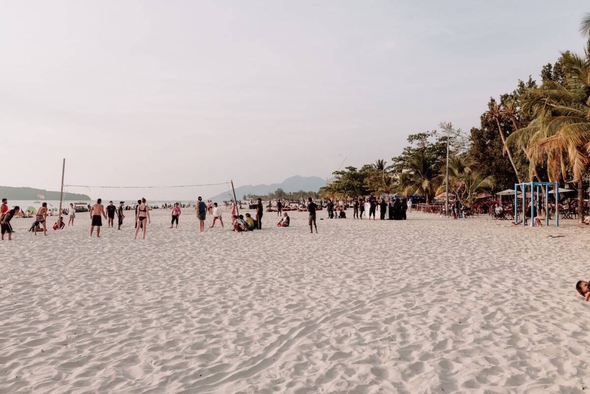 Menschen spielen Beachvolleyball an einem tropischen Sandstrand