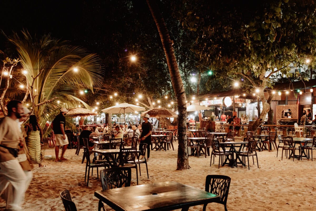 Strandrestaurant bei Nacht mit Lichterketten und Palmen