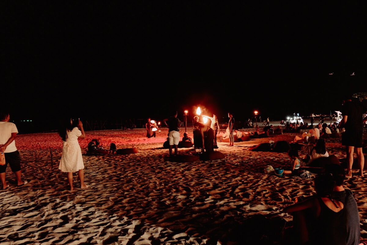 Feuershow am Strand bei Nacht mit Zuschauern
