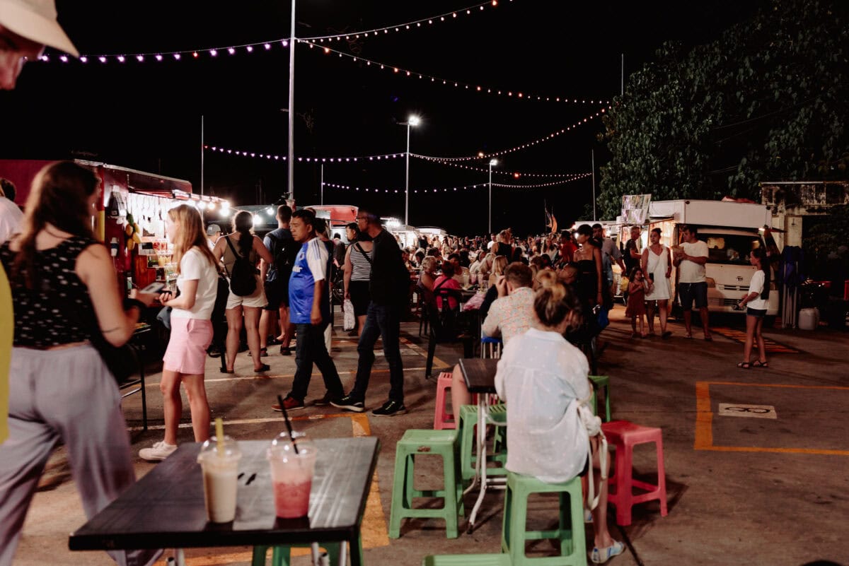 Belebter Nachtmarkt mit Lichterketten und vielen Menschen