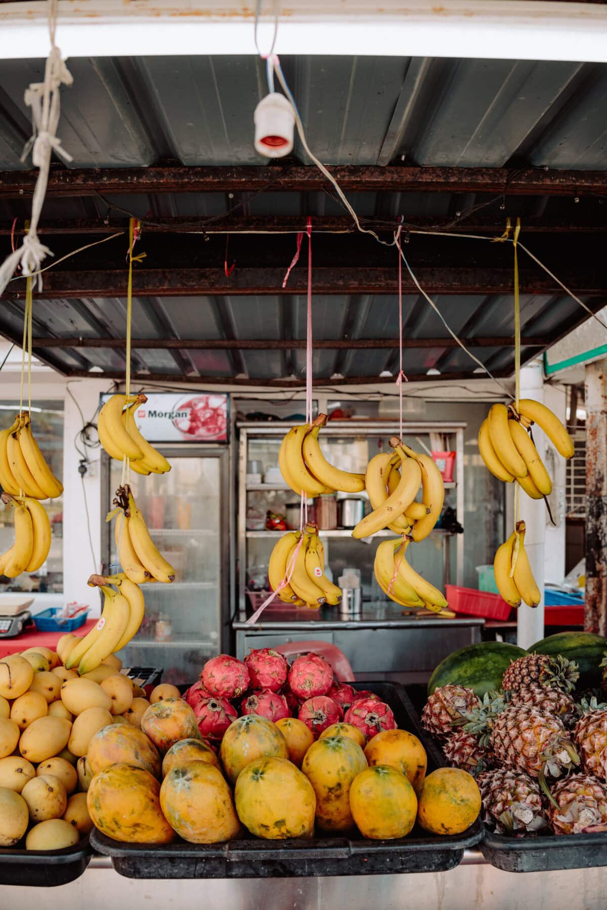 Tropischer Marktstand mit Bananen, Mangos, Drachenfrucht und Ananas